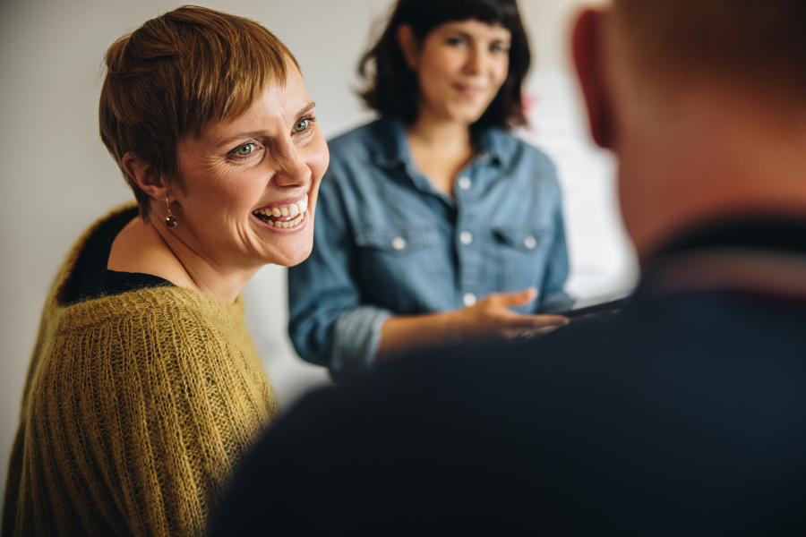 A candid photo of a woman smiling over her shoulder at a colleague